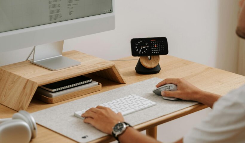 A clean and modern desk setup featuring a computer, clock, and accessories in a home office.